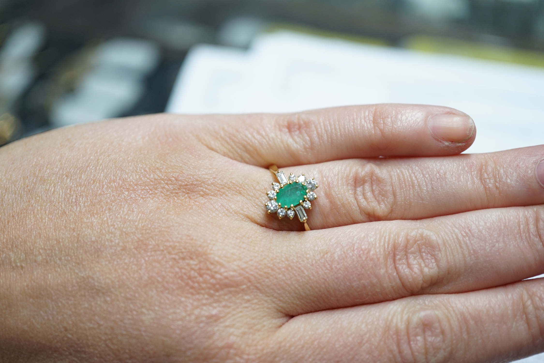 A modern 18ct gold, single stone oval cut emerald and round and baguette cut diamond cluster set ring, size P/Q, size 3 grams.
